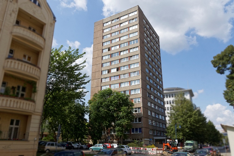 Automatisch gespeicherter Entwurf: Hochhausfassade in der Gubener-Strasse mit vielen Fenstern und umliegenden Bauten.