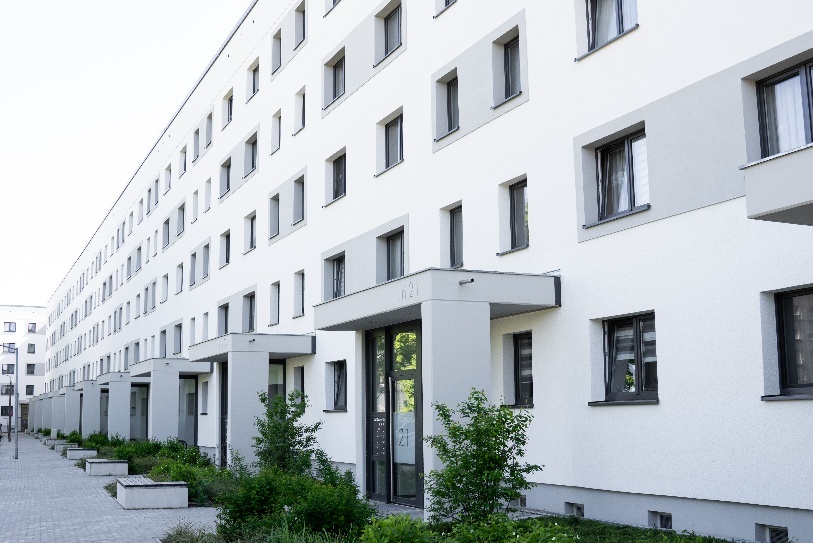 Ansicht eines sanierten Wohnkomplexes Juri-Gagarin-Ring. Die Fassade ist weiß mit grauen Akzenten und vielen Fenstern. Wohnzukunft Investition.